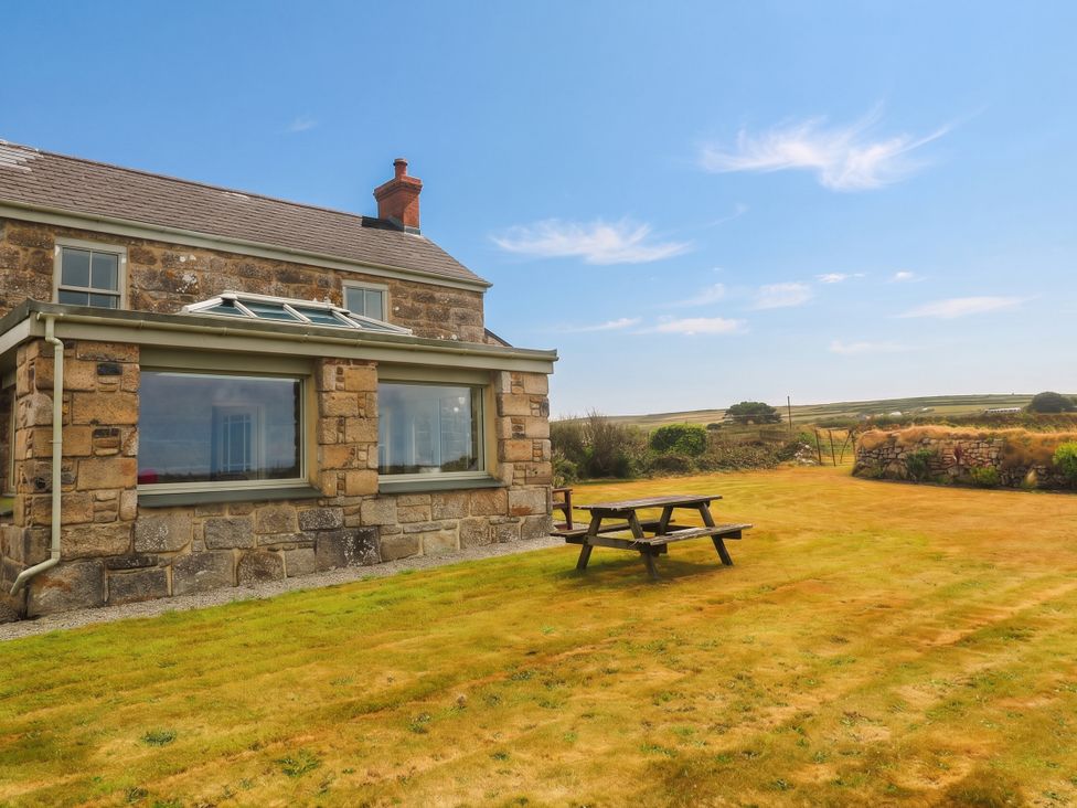 A house with a lawn and a table outside at Chyrose Farmhouse Pendeen