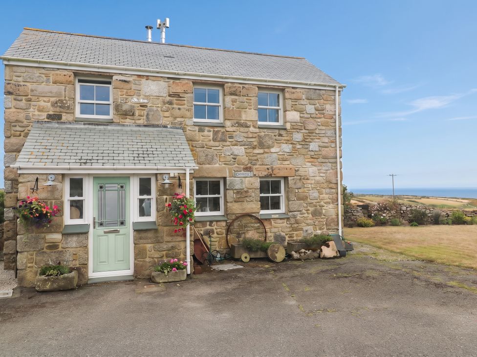 A house with a green door and flower pots at Chyrose Farmhouse in Pendeen