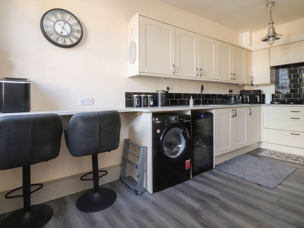 A kitchen with a washing machine and bar stools at 10 Oak Street in Keighley