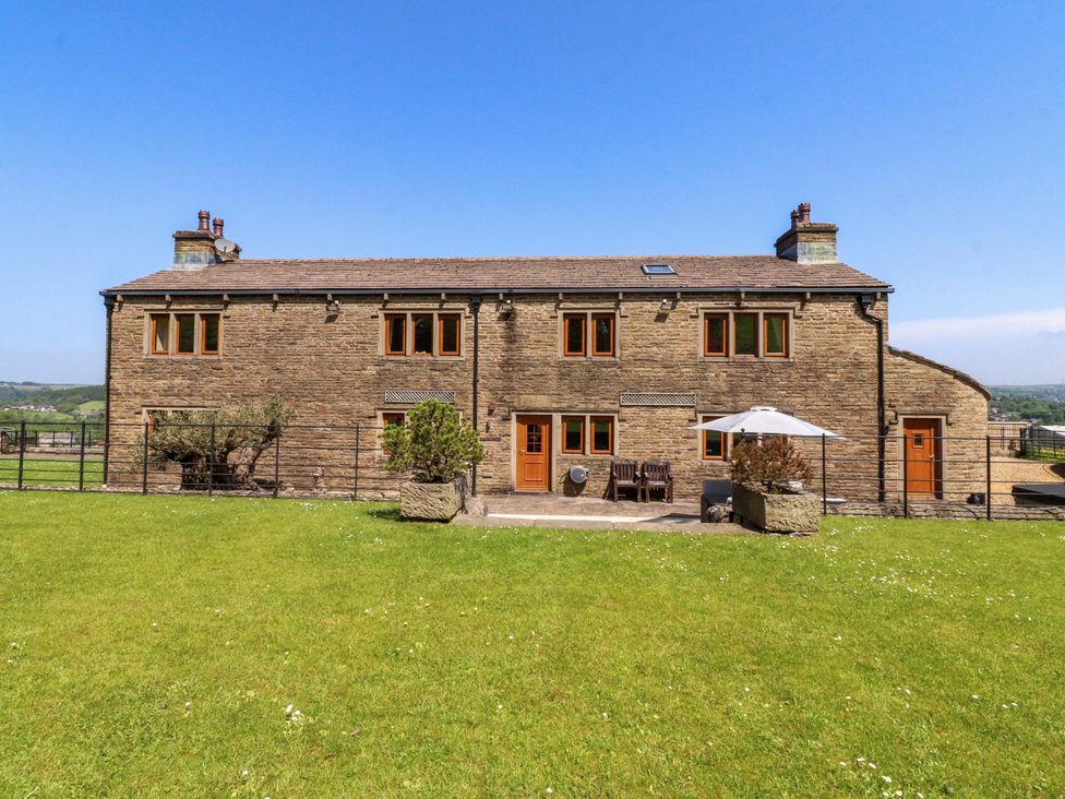 An outdoor view of a stone house with a patio at Sheephouse Farm in Bacup