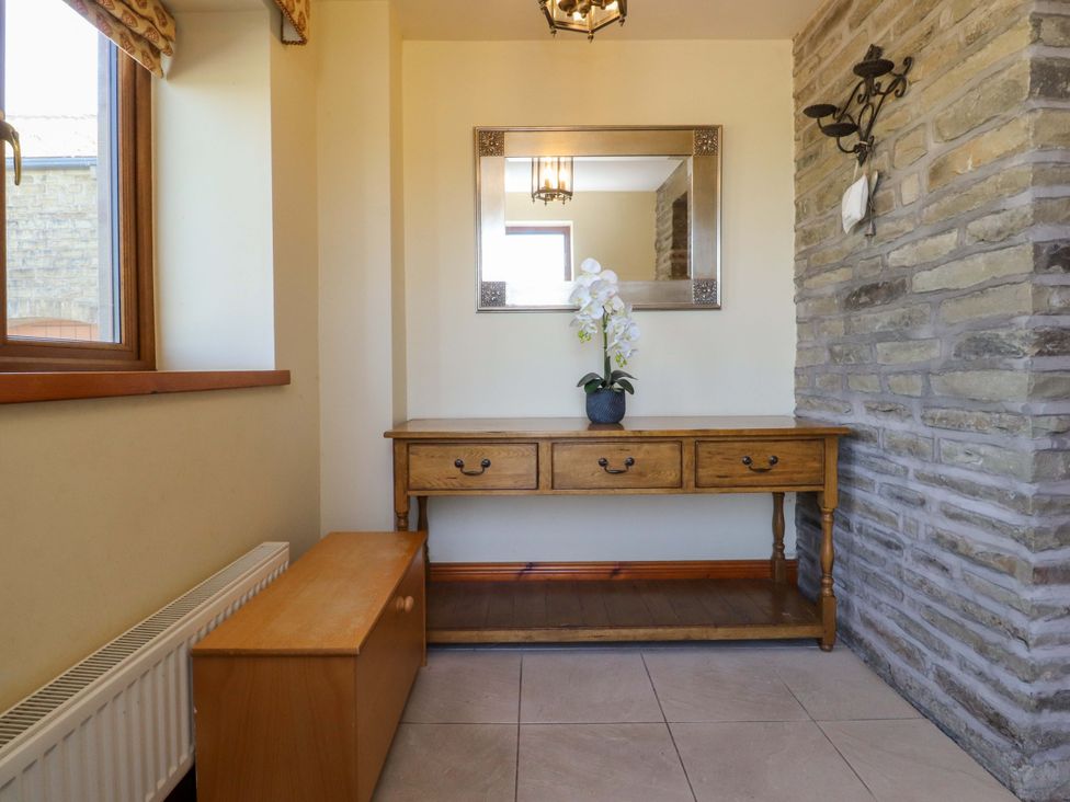 A hallway with a table and mirror at Sheephouse Farm in Bacup