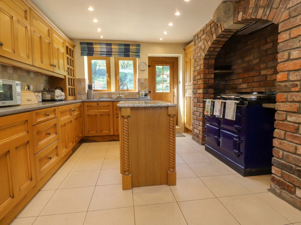 A kitchen with wooden cabinets and a brick oven at Sheephouse Farm in Bacup