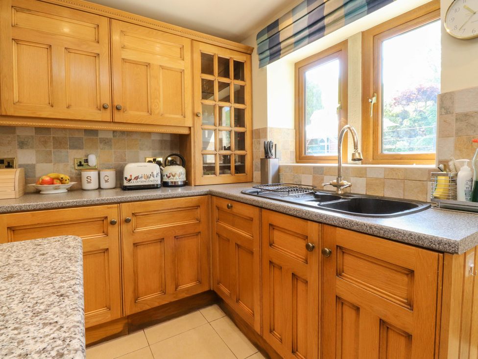 A kitchen with wooden cabinets and a sink at Sheephouse Farm in Bacup