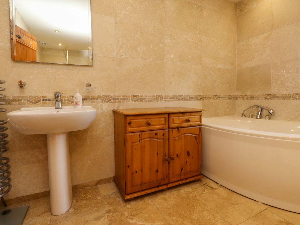 A bathroom with a sink, cabinet, and bathtub at Sheephouse Farm in Bacup