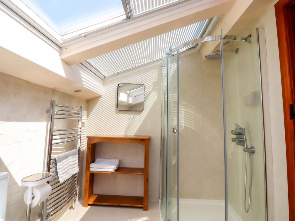 A bathroom with a shower, towel rail, and wooden shelf at Sheephouse Farm in Bacup