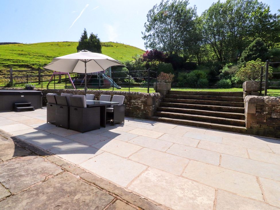 A garden with a table and chairs under an umbrella at Sheephouse Farm in Bacup