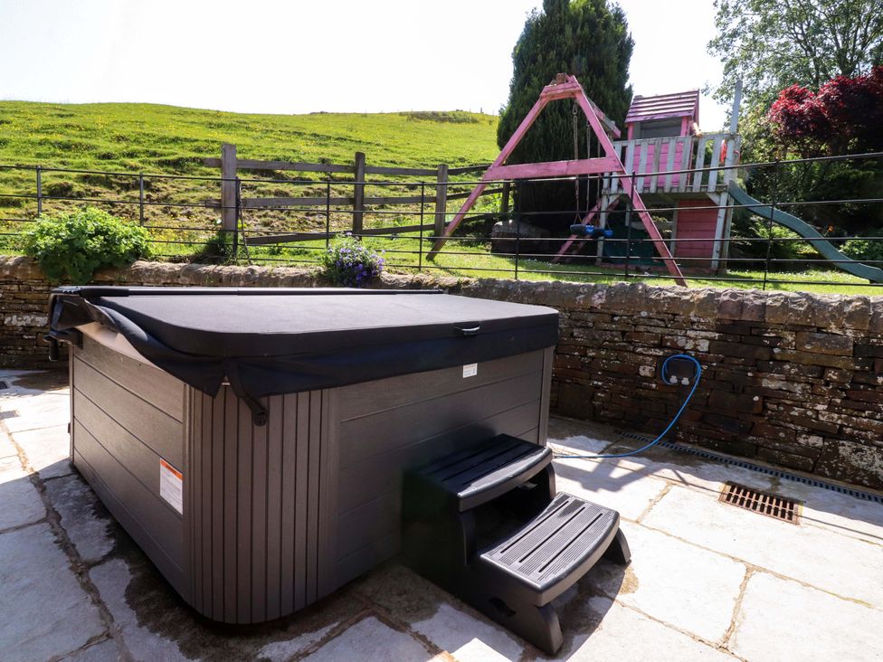 A garden with a hot tub and play equipment at Sheephouse Farm in Bacup