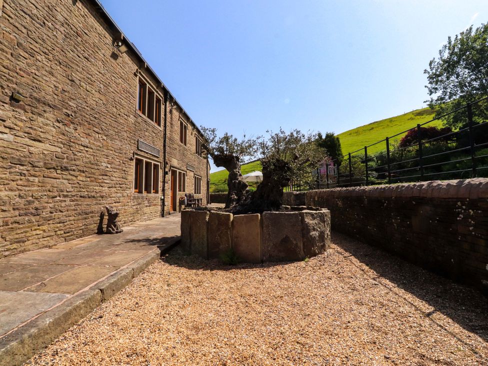 An outdoor area with a stone building and gravel path at Sheephouse Farm in Bacup