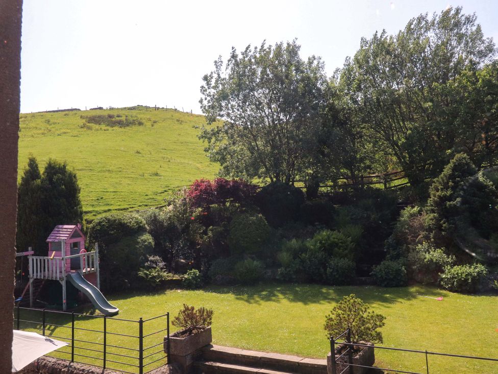 A garden with a playhouse and slide at Sheephouse Farm in Bacup