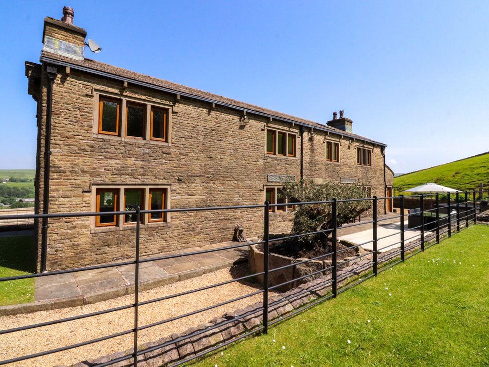A stone house with windows and a patio at Sheephouse Farm in Bacup