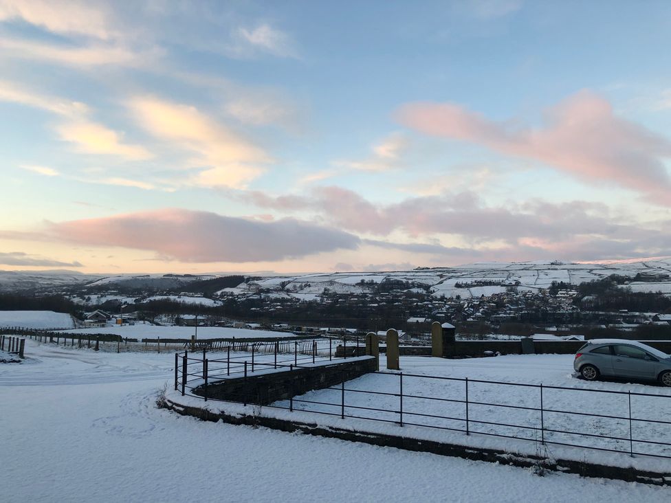 A snowy landscape with a car and hills at Sheephouse Farm in Bacup