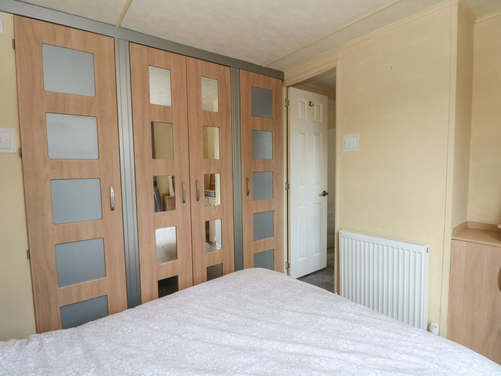 A bedroom with wardrobe and bed at Hawks View Caravan in Macclesfield