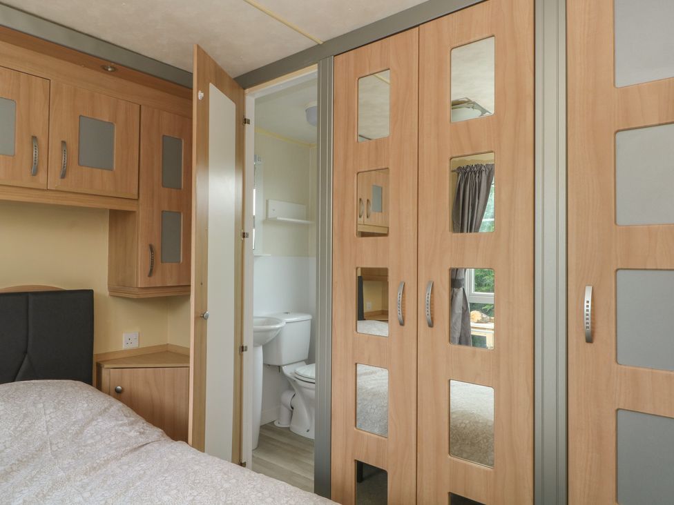 A bedroom with a bed and wardrobe at Hawks View Caravan in Macclesfield