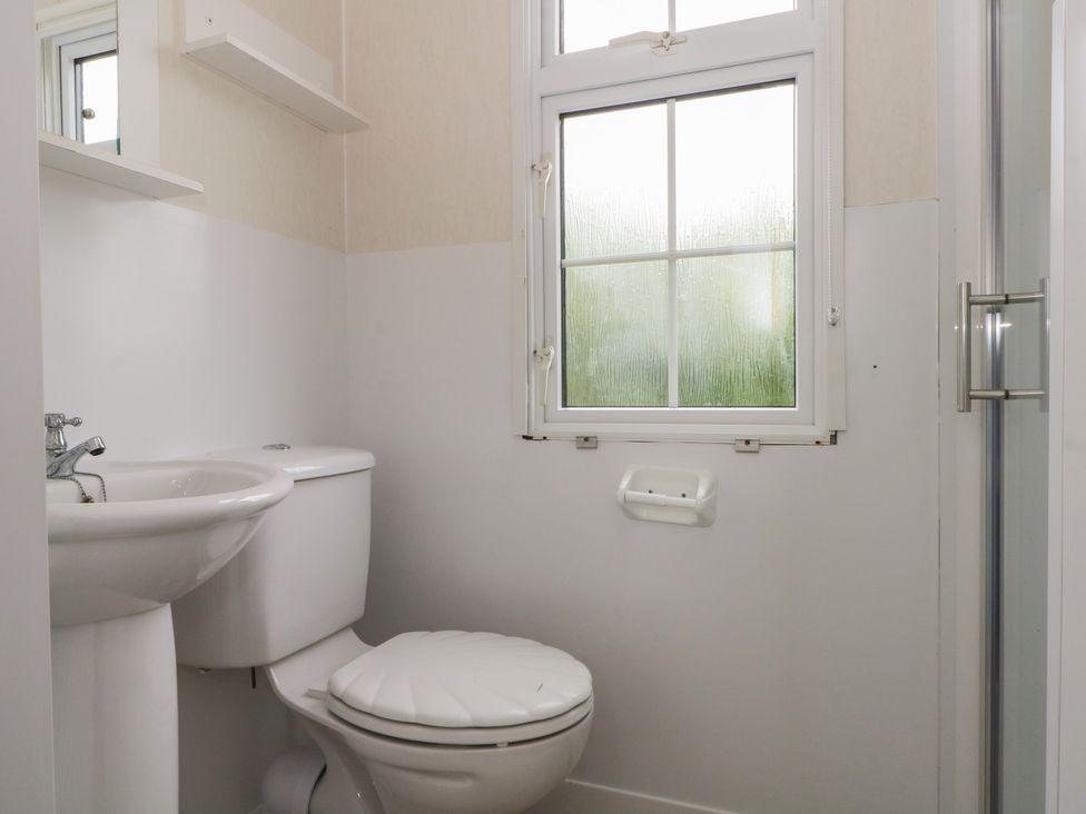A bathroom with a toilet, sink, and shower at Hawks View Caravan in Macclesfield