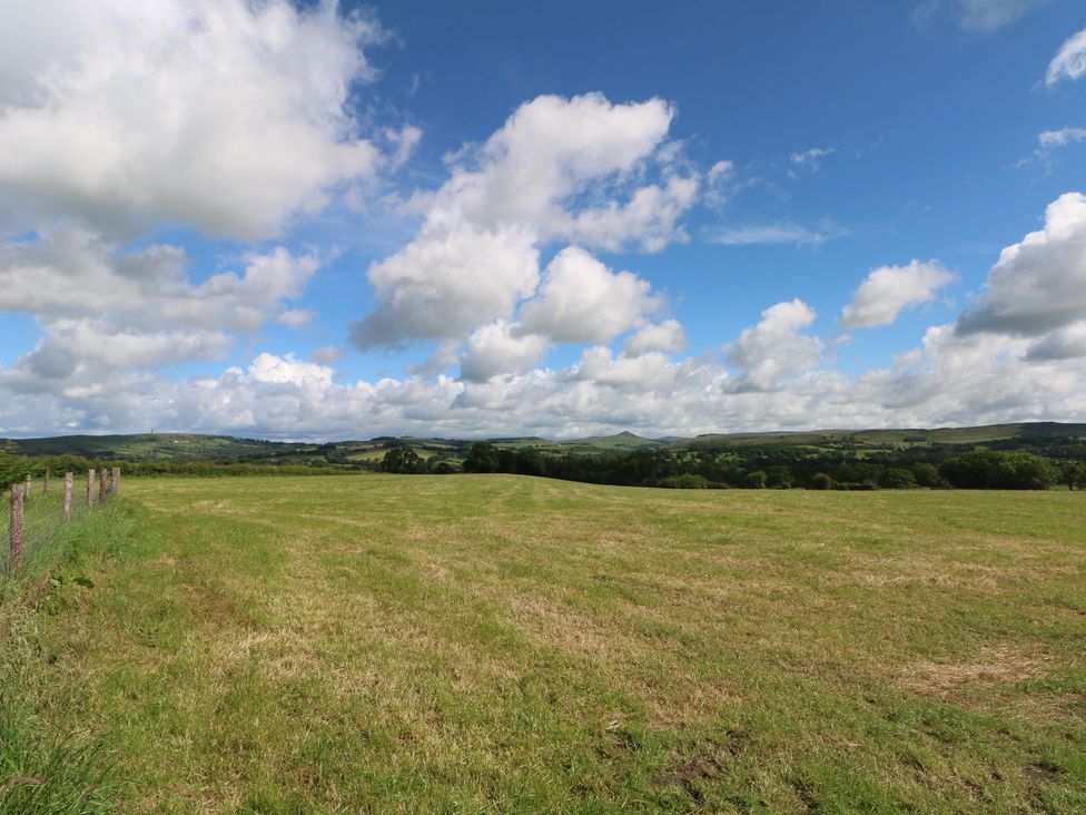 A field with grass and a fence against a backdrop of hills at Hawks View Caravan in Macclesfield