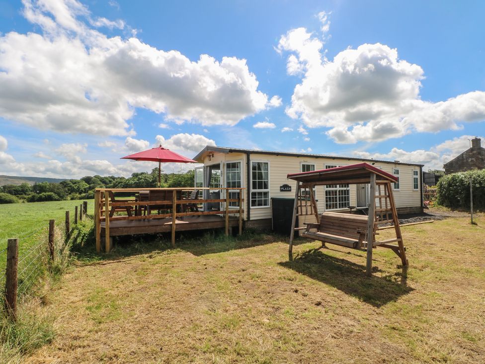 A caravan with a deck and swing at Hawks View Caravan in Leek
