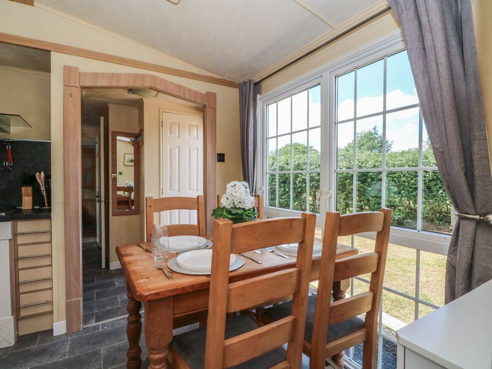 A dining room with a wooden table and chairs at Hawks View Caravan in Leek
