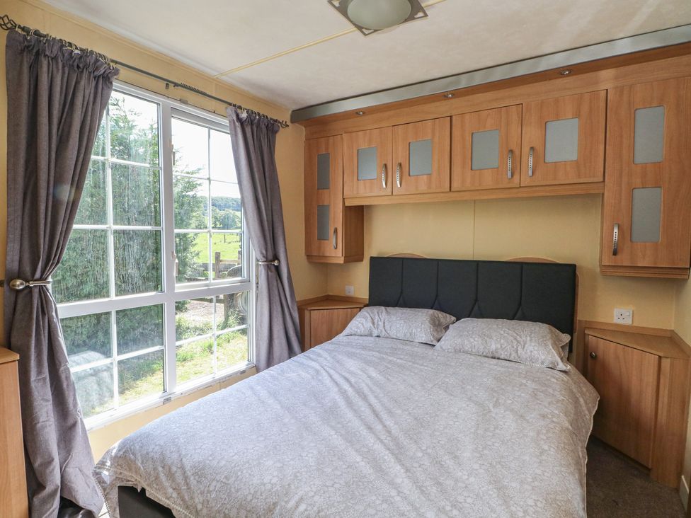 A bedroom with a bed and cabinets at Hawks View Caravan in Leek
