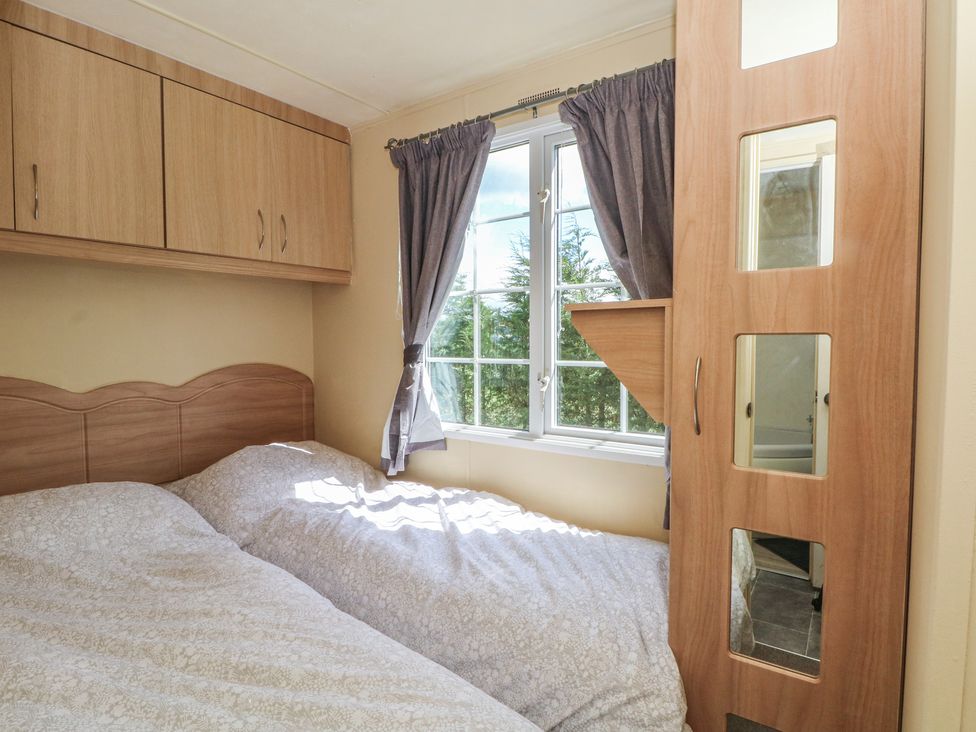A bedroom with a double bed and window at Hawks View Caravan in Leek