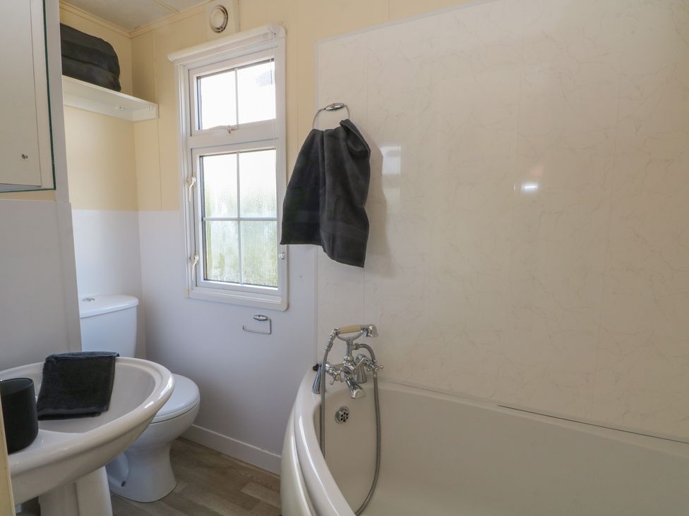 A bathroom with a bathtub, toilet, and sink at Hawks View Caravan in Leek