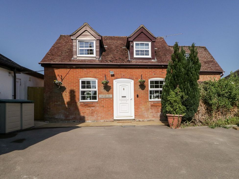 A brick house with a front door and windows at The Cottage in Winterslow