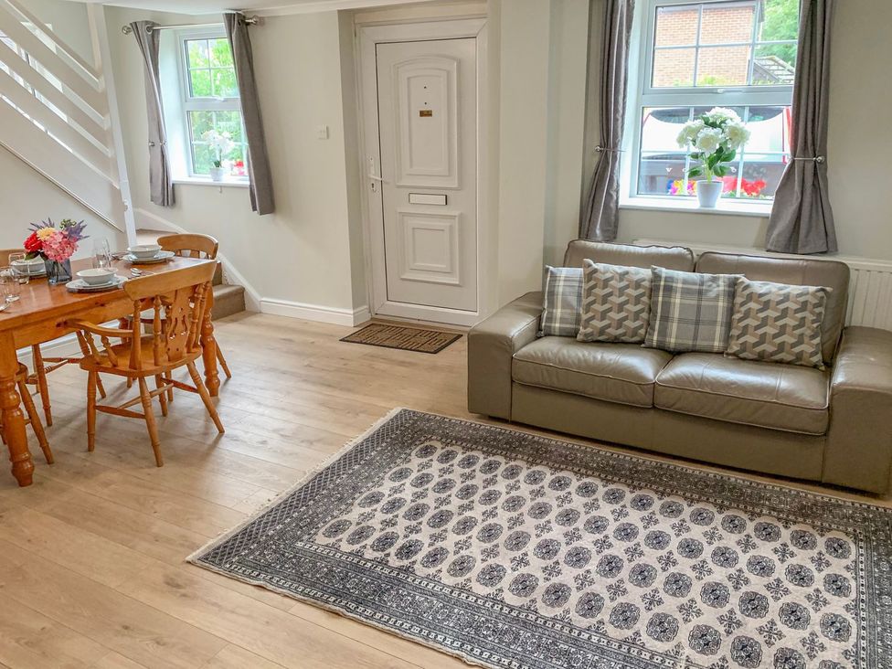 A living room with a sofa and dining area at The Cottage in Winterslow
