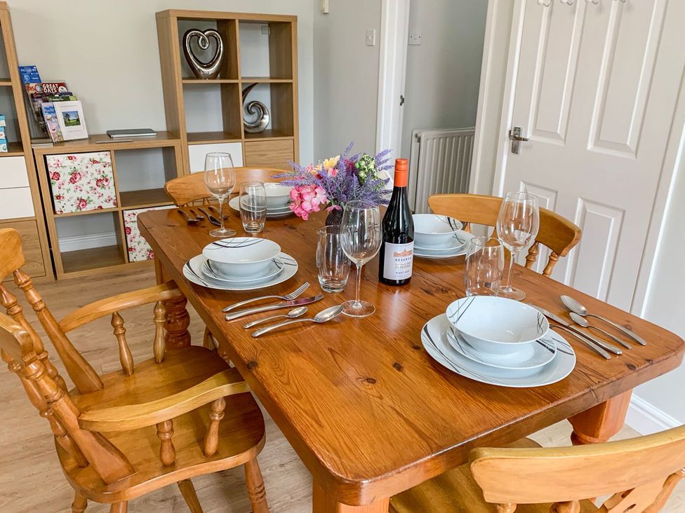 A dining room with a wooden table set for a meal at The Cottage in Winterslow
