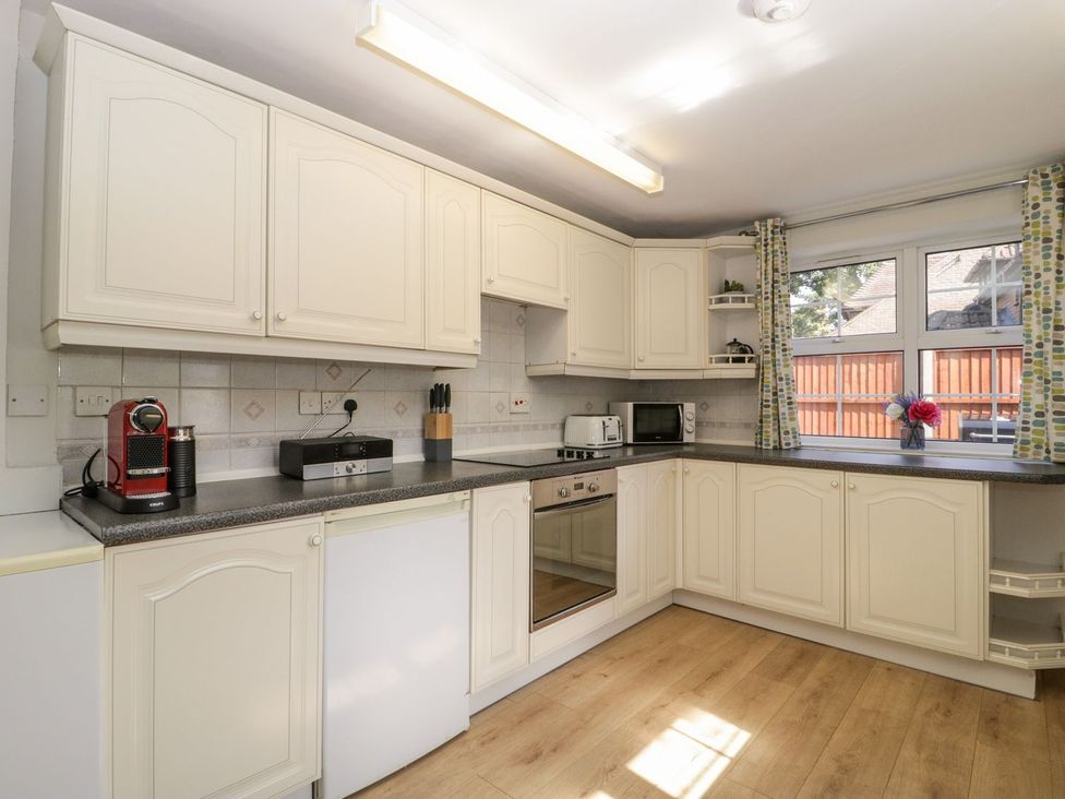 A kitchen with cabinets, appliances and a window at The Cottage in Winterslow