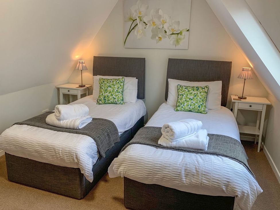 A bedroom with two beds and a bedside table at The Cottage in Winterslow