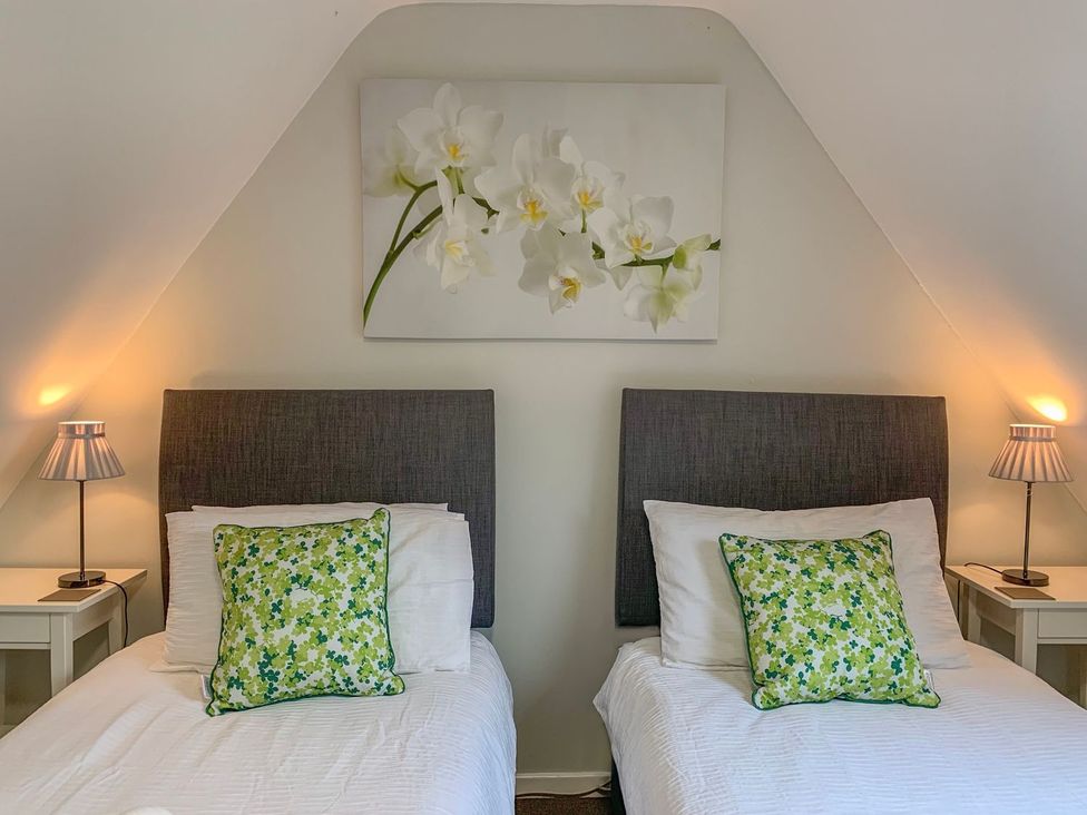 A bedroom with two single beds and wall art at The Cottage in Winterslow