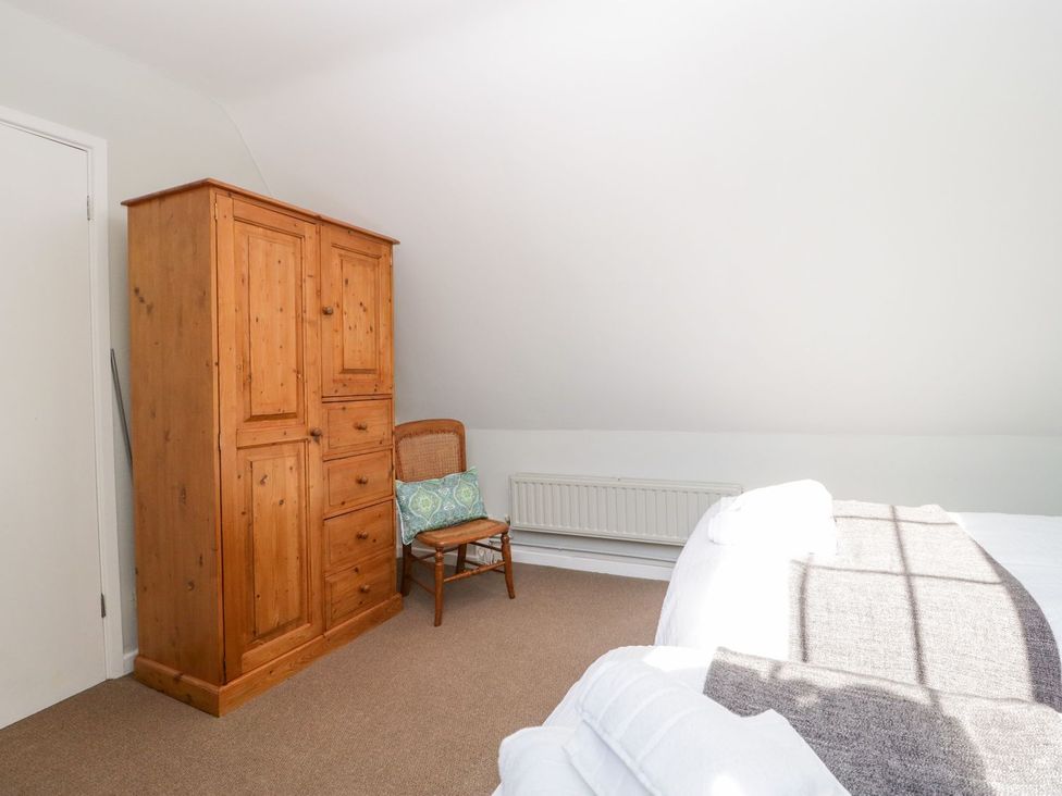 A bedroom with wardrobe and chair at The Cottage in Winterslow