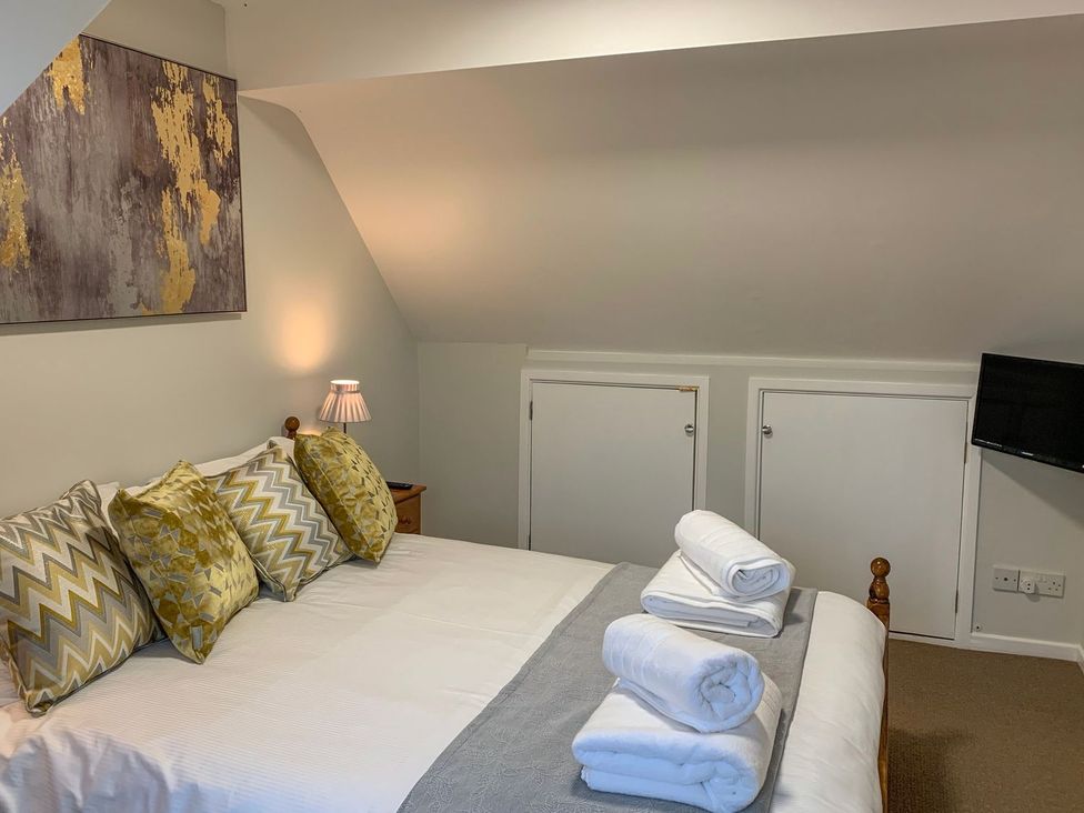 A bedroom with a bed and cushions at The Cottage in Winterslow