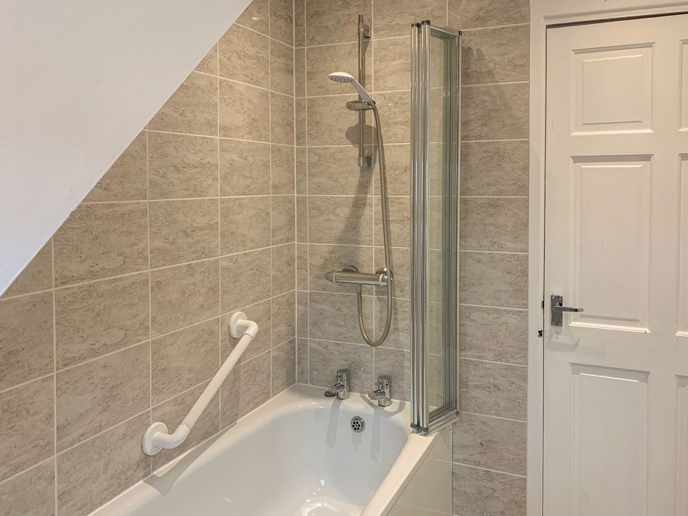 A bathroom with a bathtub and shower at The Cottage in Winterslow