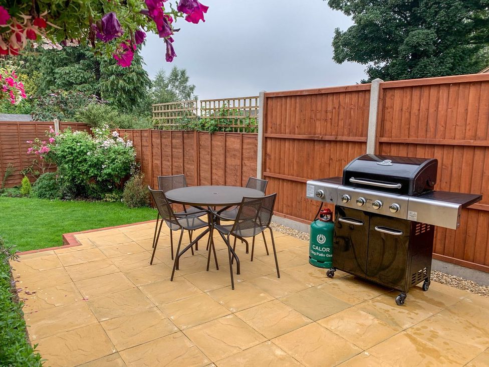 A garden with a table, chairs and a barbecue grill at The Cottage in Winterslow