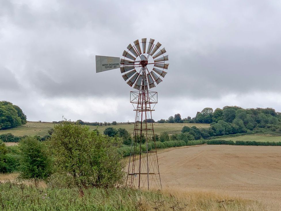 A windmill in a field with trees in the background at The Cottage in Winterslow