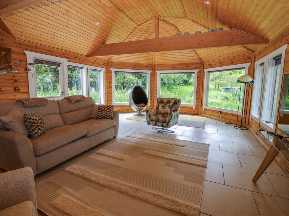 A snug area with a sofa and chair at Bull Rush Cabin Carwinley near Longtown
