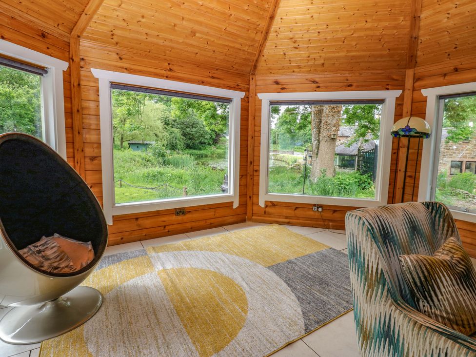 A snug with a chair and rug at Bull Rush Cabin Carwinley near Longtown