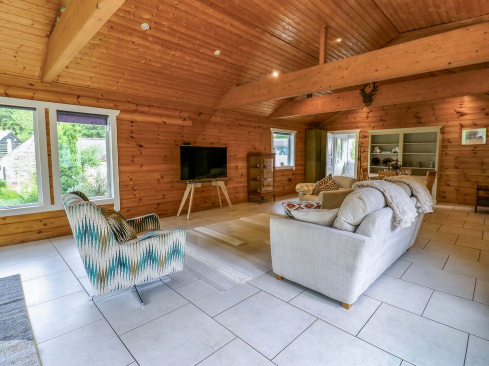 A living room with a sofa and television at Bull Rush Cabin near Longtown