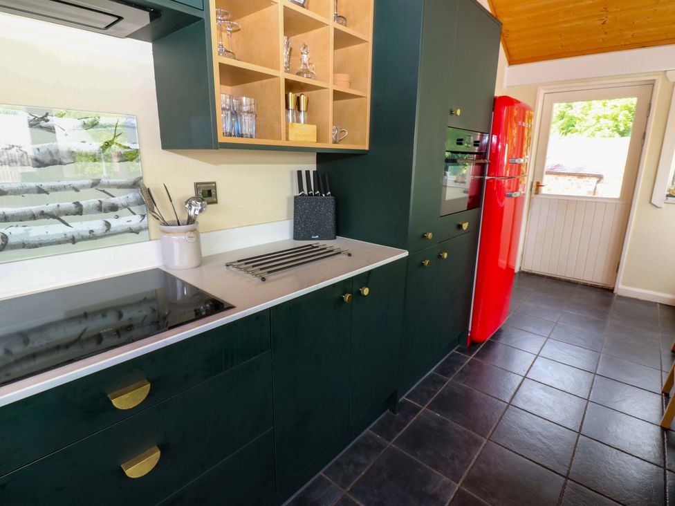 A kitchen with cabinets and a red refrigerator at Bull Rush Cabin in Carwinley near Longtown