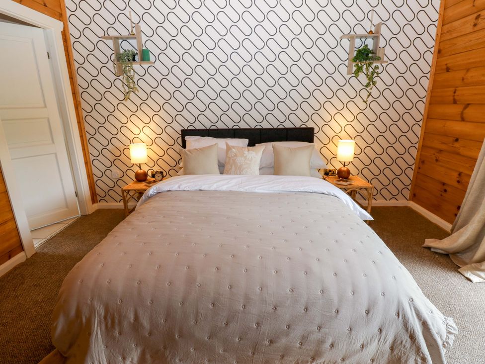 A bedroom with a bed and bedside tables at Bull Rush Cabin Carwinley near Longtown