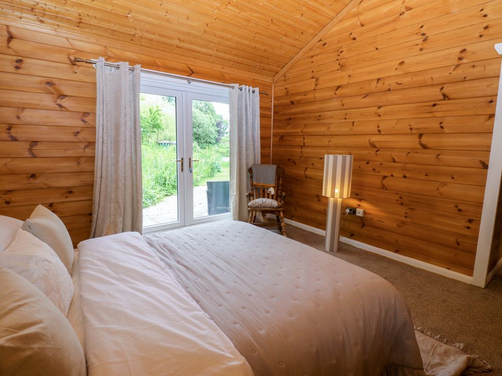 A bedroom with a bed and a sliding door at Bull Rush Cabin in Carwinley near Longtown