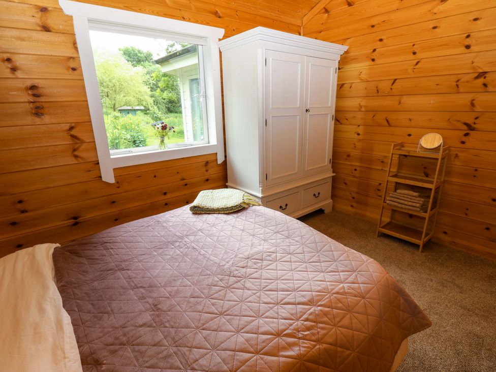 A bedroom with a bed and wardrobe at Bull Rush Cabin in Carwinley near Longtown