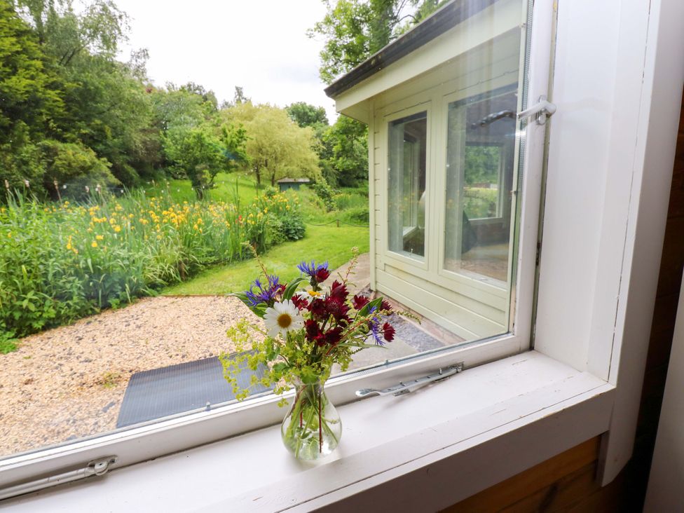 A window with a flower vase in front at Bull Rush Cabin Carwinley near Longtown