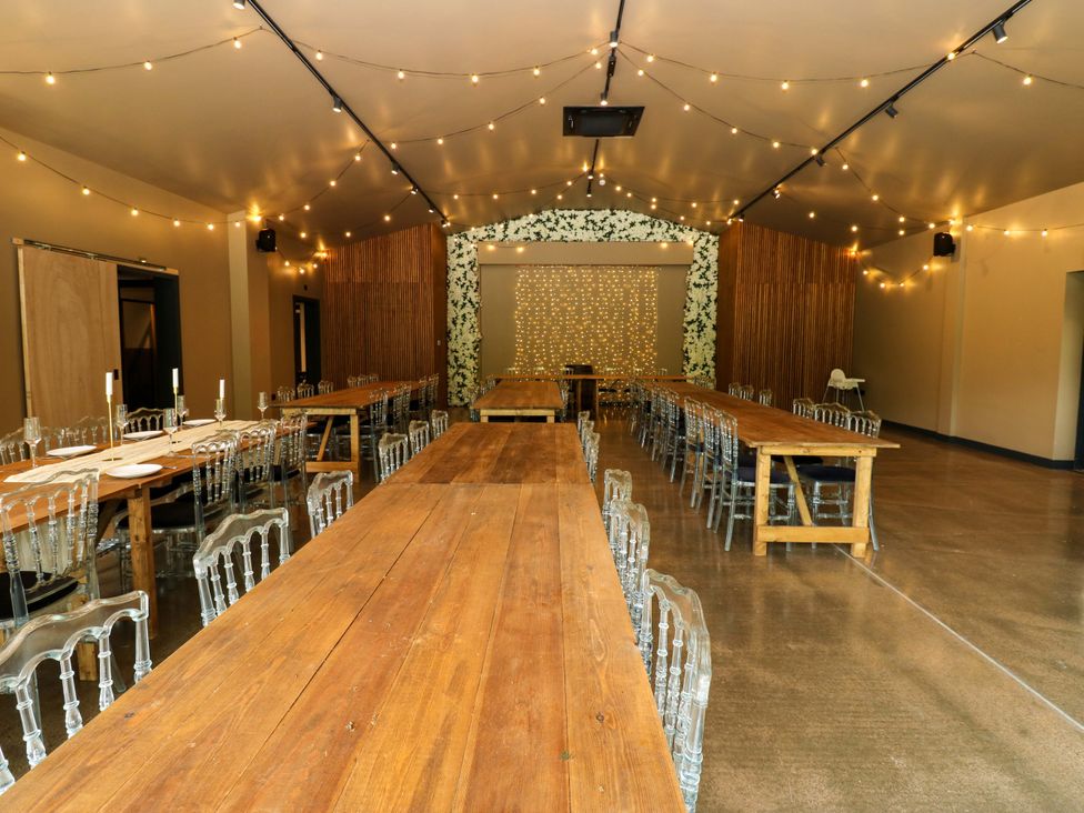 A dining hall with long tables and transparent chairs at Bull Rush Cabin Carwinley near Longtown