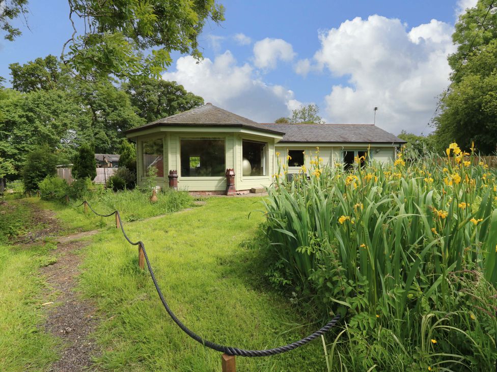 A house surrounded by grass and flowers at Bull Rush Cabin in Carwinley near Longtown