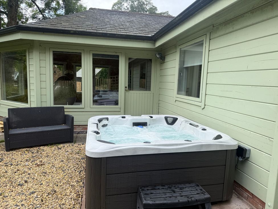 An outdoor area with a hot tub and a sofa at Bulrush Cabin Carwinley near Longtown