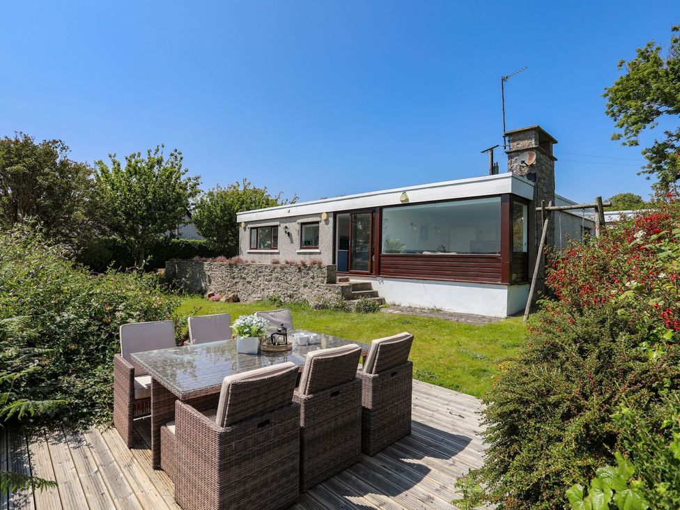 A garden with a dining table and chairs at Bryn Llifon in Pentraeth