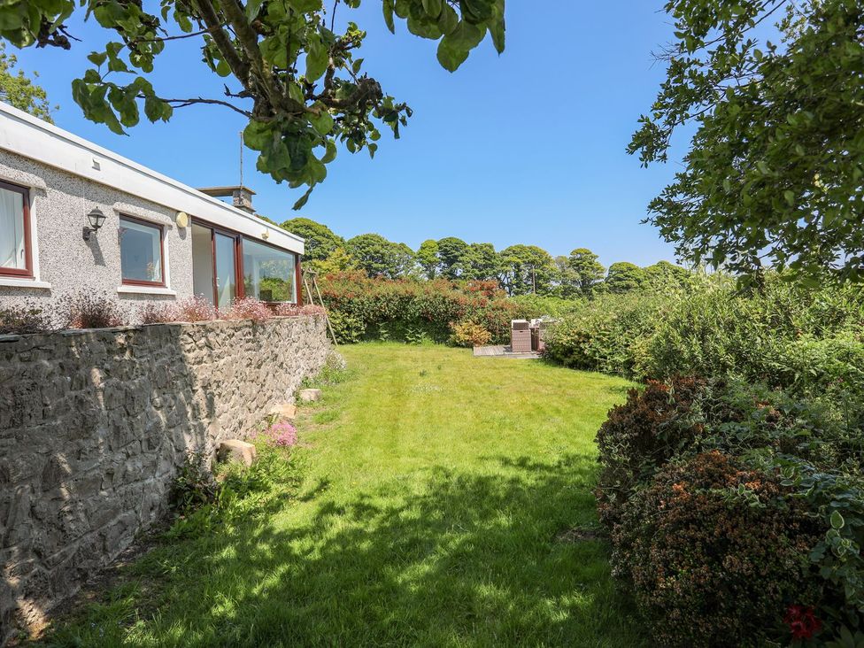 A garden with grass and trees at Bryn Llifon in Pentraeth