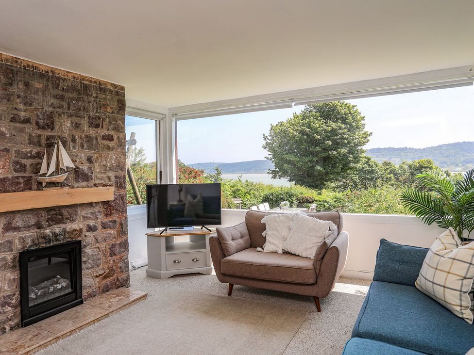 A living room with a television and a fireplace at Bryn Llifon in Pentraeth