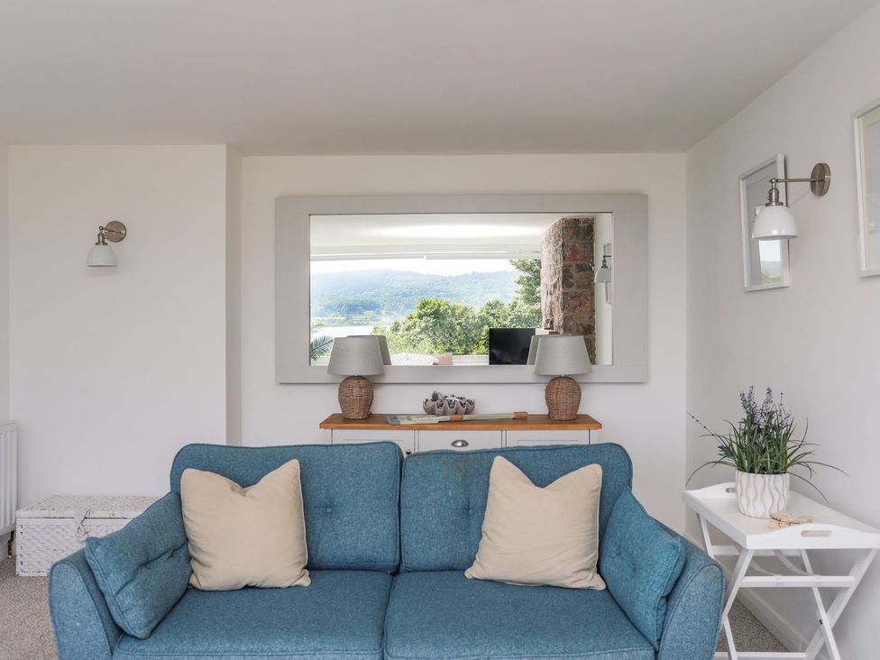 A living room with a sofa and a lamp at Bryn Llifon in Pentraeth